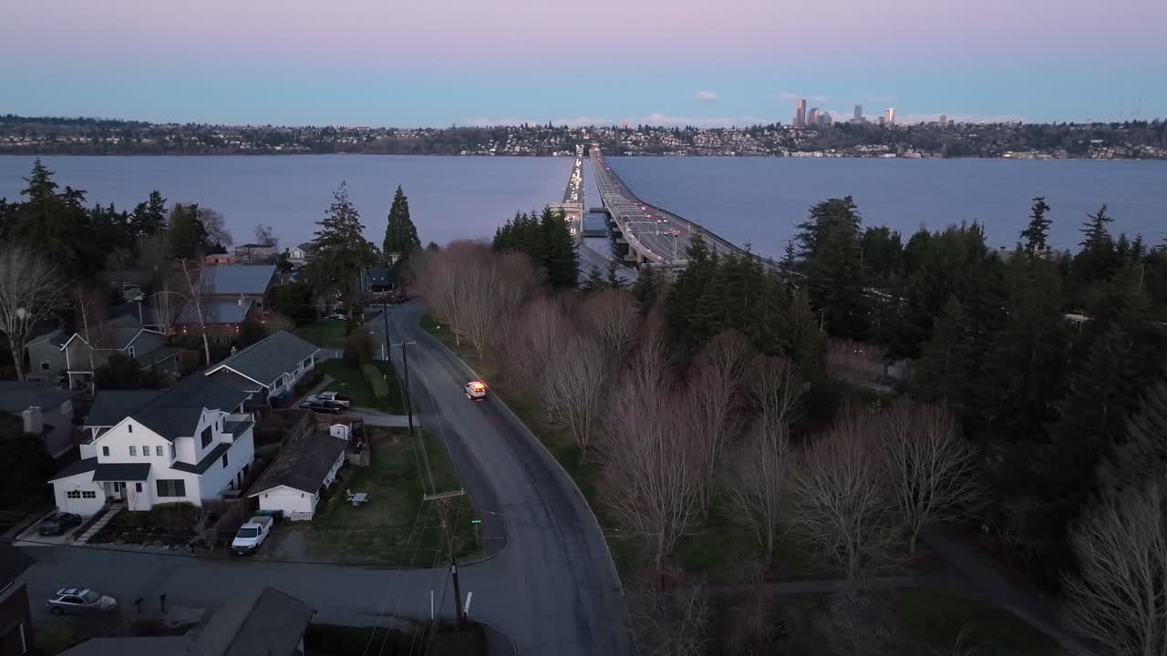 Drone captures the journey of a vehicle with emergency lights, possibly an ambulance or roadside assistance, as it makes its way to the scenic coastal area of Seattle, Washington.