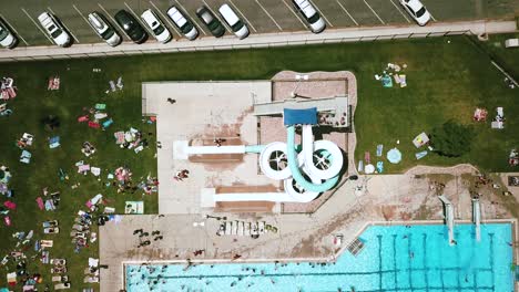 rising drone shot of a large twisty double-waterslide at an outdoor public pool