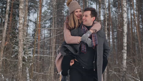 Happy-Couple-is-Playing-Winter-Game-Outside-Enjoying-Sunlight-and-Warm-Winter-Weather-in-the-Mountains.-Strong-Boy-is-Carrying-Girlfriend-on-His-Shoulders-and-Whirls-Her