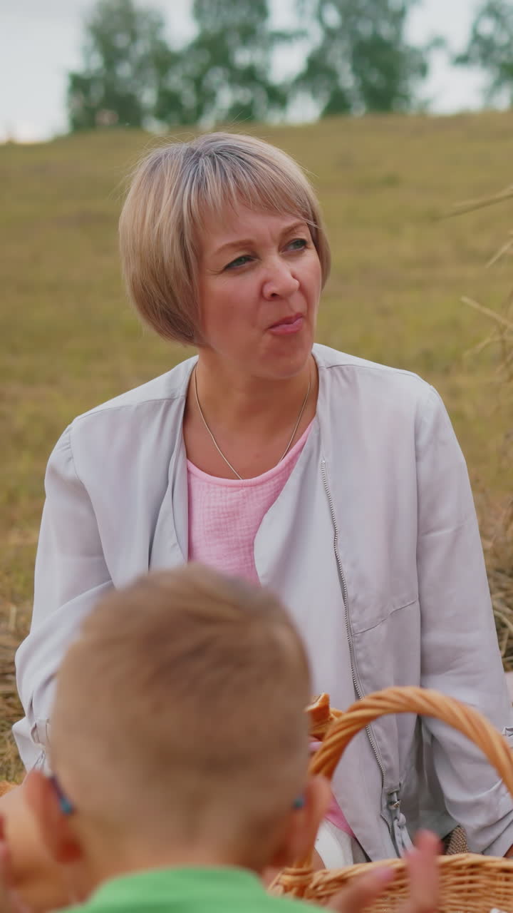 밖에서 앉아있는 두 아이의 뒷면, 어머니가 조용히 물고기 롤을 는 동안, 그녀의 이모는 평화로운 야외에서 그들의 에 피크닉 바구니를 가지고 즐기고 있습니다.