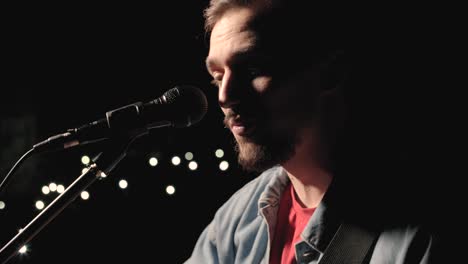 a musician is playing guitar on a large stage with audience members holding flashlights in the background. the auditorium is filled with beautiful flashing lights.