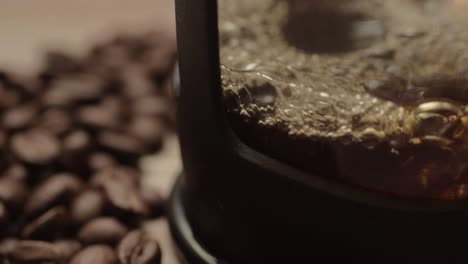 pouring fresh coffee into a pot with coffee beans