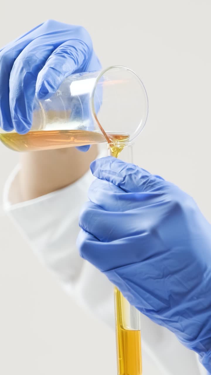 Scienziato che versa del liquido da un becher in una provetta