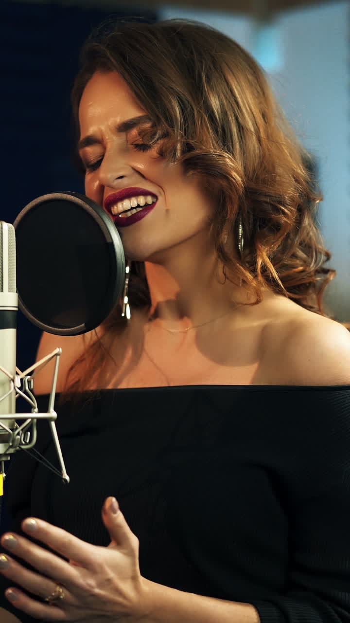 Beautiful young singer who recorded a song in a professional recording studio. Female vocal Vertical video
