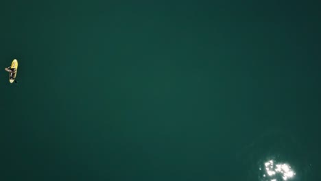노란색 스탠드업 패들에 있는 스탠드업 패들러의 공중, 드론 하향식 샷