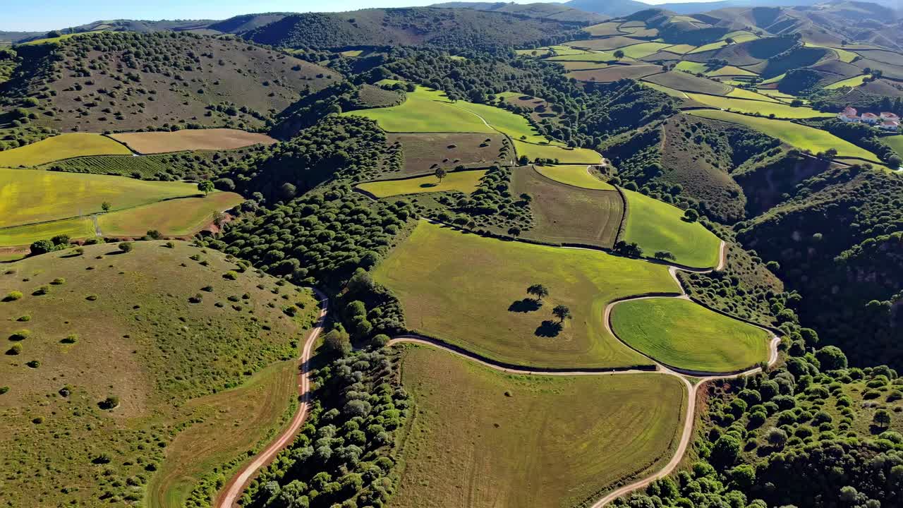 Aerial video captures rolling hills with lush green fields and winding roads