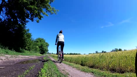 young woman riding vintage bicycle along a rural road in a village