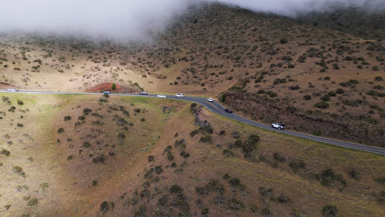 los turistas suben al volcán haleakala a través de las nubes hacia el parque nacional en una sinuosa carretera de montaña