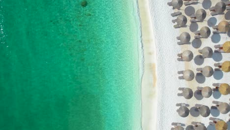 Top-Down-View-Over-The-Beautiful-Marble-Beach,-With-Crystal-Clear-Water,-White-Pebbles,-Lush-Green-Vegetation,-Umbrellas-And-Sunbeds,-Empty-Beach,-Thassos-Island,-Greece