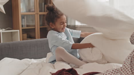 kids having pillow fight on bed