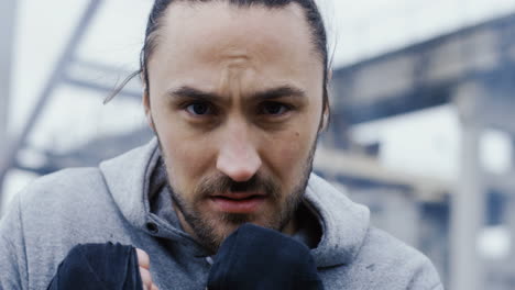 caucasian sportsman boxing to the camera outdoors an abandoned factory on a cloudy morning