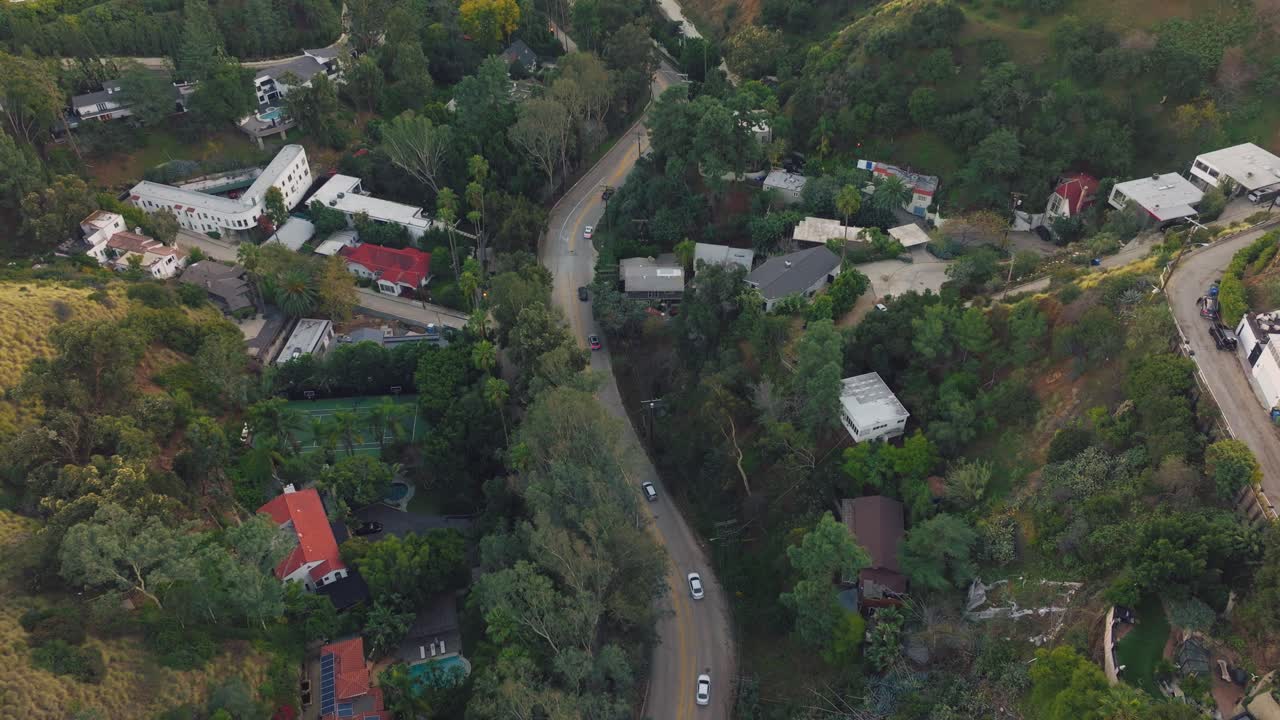 Sorvolando auto su una strada tortuosa attraverso Laurel Canyon, un pittoresco quartiere di colline ondulate a Los Angeles di giorno