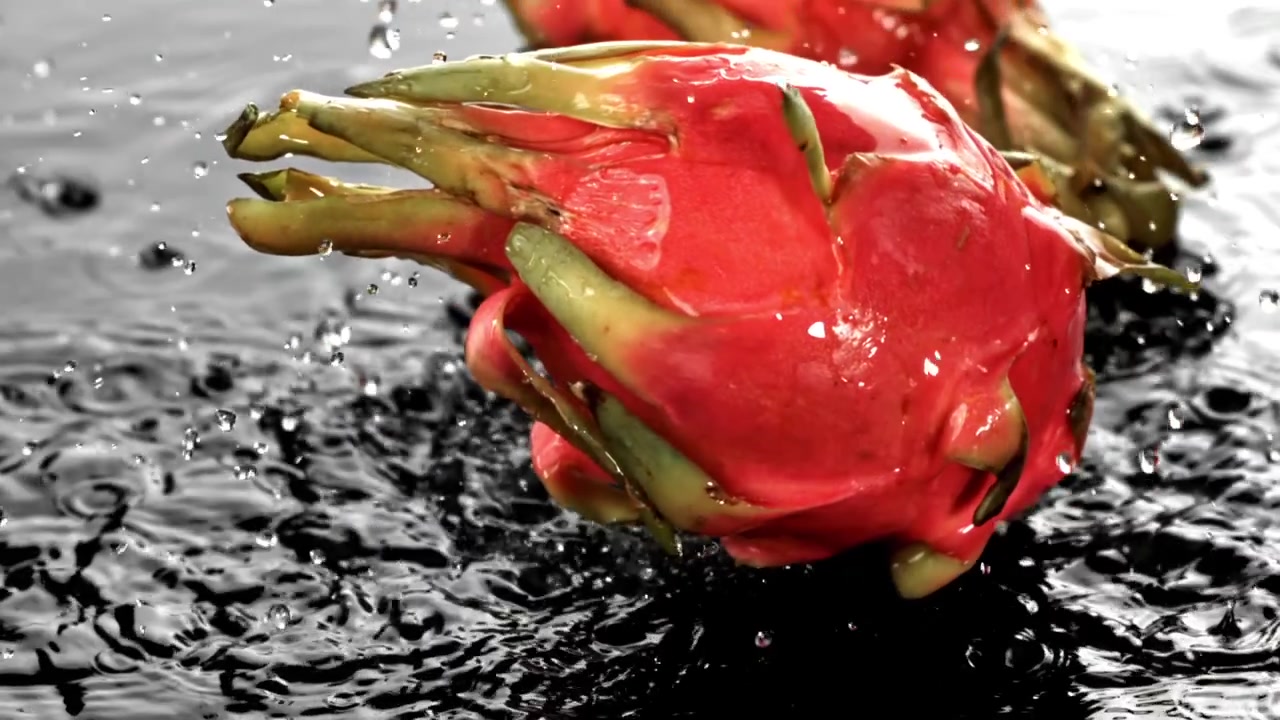 Gocce d'acqua al rallentatore che schizzano su un fresco frutto del drago rosso