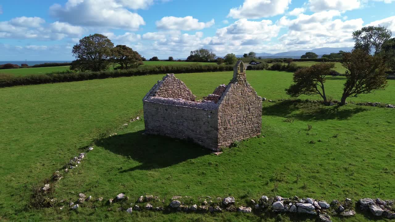Lligwy chapel aerial view circles around medieval churchyard ruins on lush coastal Welsh meadow