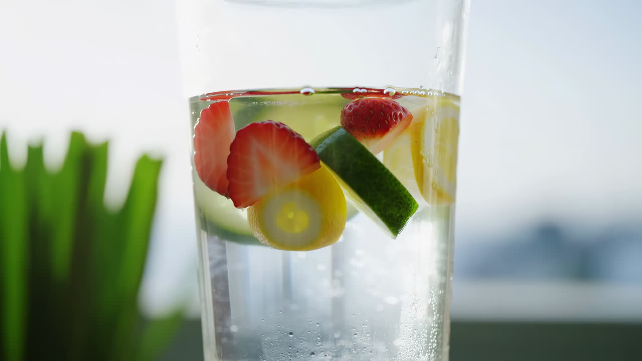 Acqua detox rinfrescante con fette di fragola, limone, lime e cetriolo