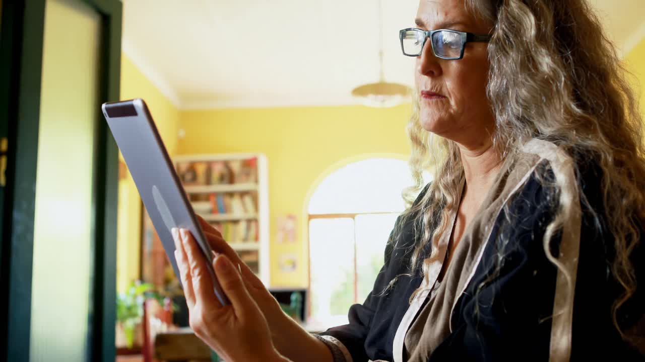mujer madura usando tableta digital en la sala de estar 4k
