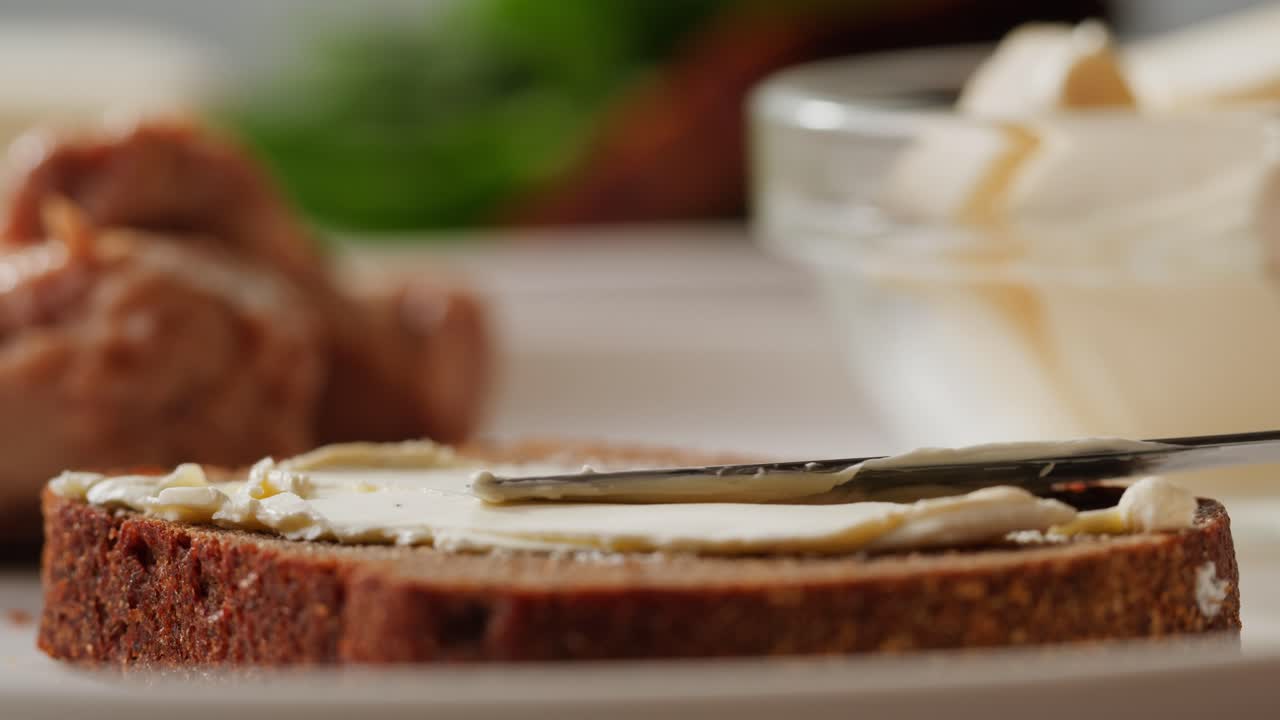 Young woman spreading nut butter onto toast in kitchen, closeup. High quality 4k footage