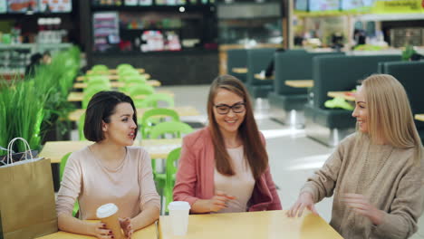 happy friends enjoying coffee in a food court