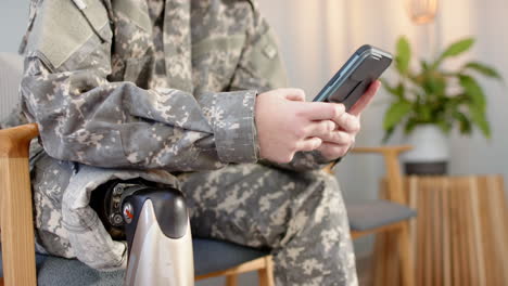 using smartphone, soldier in prosthetic leg sitting in chair, focusing on screen