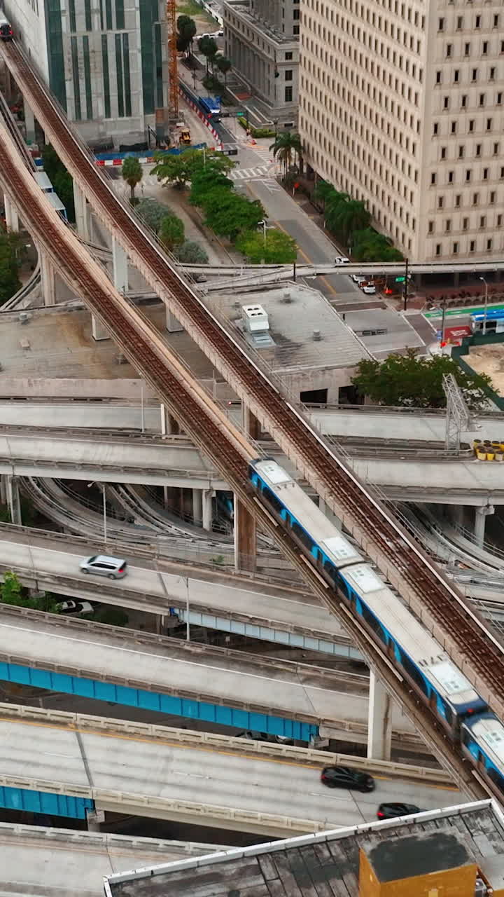 Modern transportation hub in downtown Miami. Crossroads with cars. Metro line with train. City train with weekday commuters. Vertical