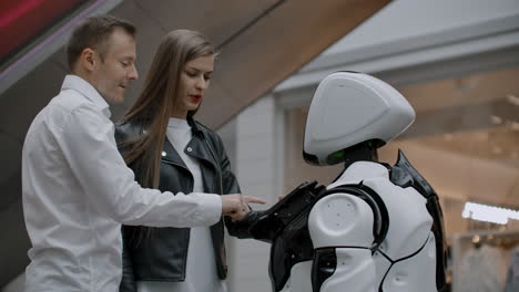 modern robotic technologies of interaction with people. friendship and communication couples with a robot. assistant to the future. the robot looks at the camera at the person. the robot shows emotions. raises his hands up dances or is independent.