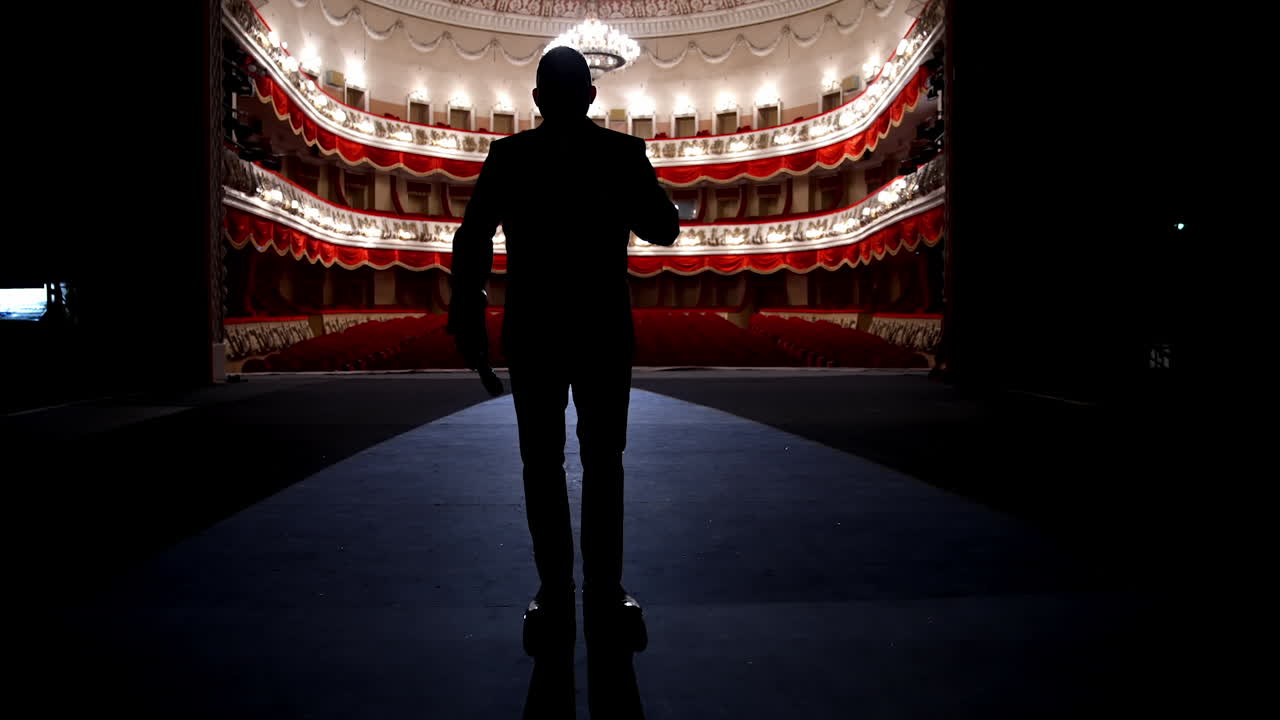 Actor walks on a scene in front of empty auditorium. Financial losses of organizers in entertainment sector because of quarantine.