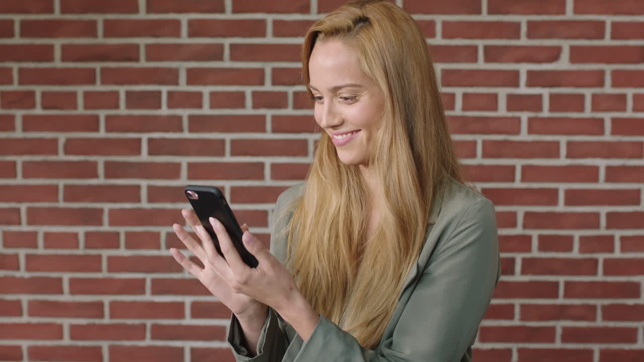 ritratto di una giovane donna bionda attraente che usa uno smartphone sorridendo allegra