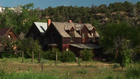 medium shot of an abandoned ranch house sitting in a grove of trees