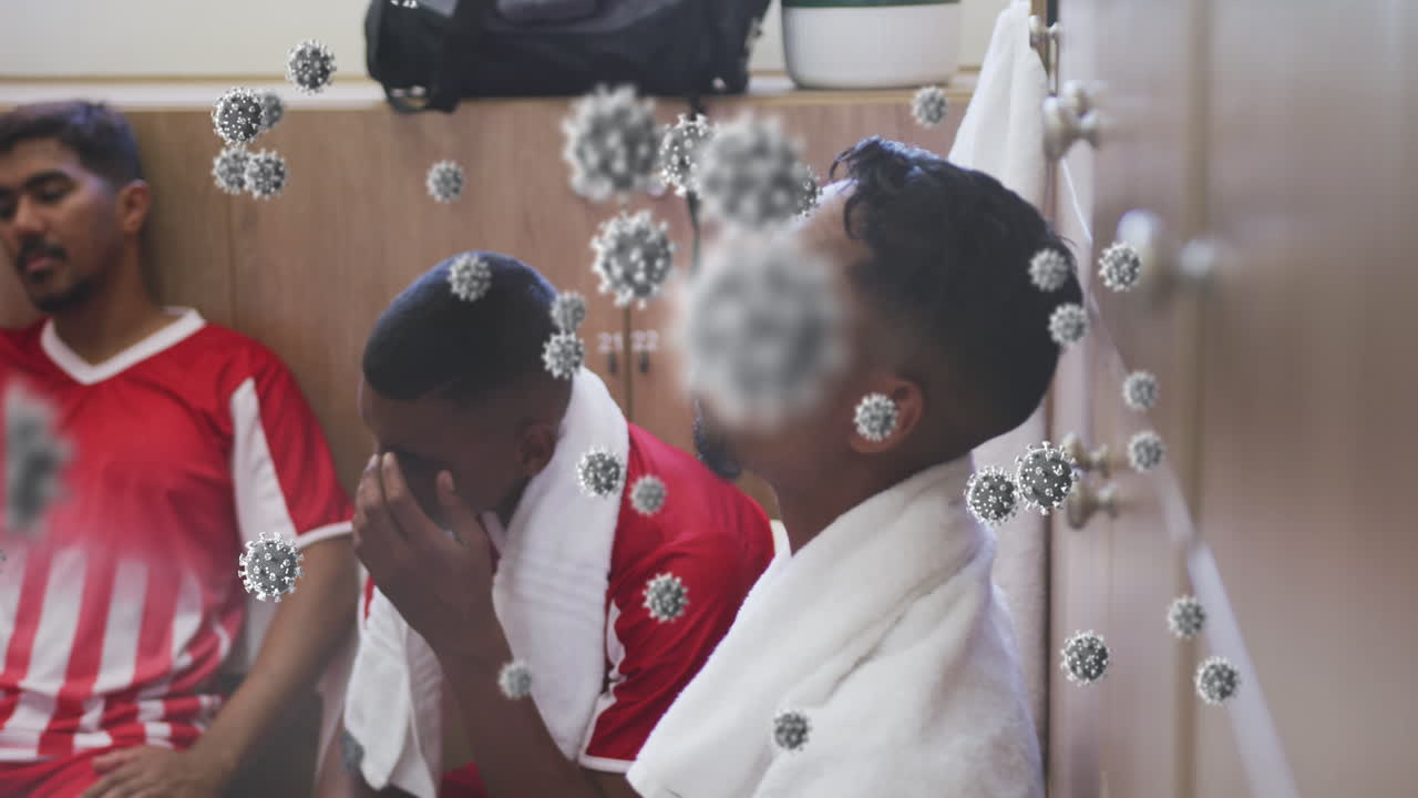 animación de células de virus flotando sobre un grupo diverso de jugadores de fútbol masculino en el vestuario