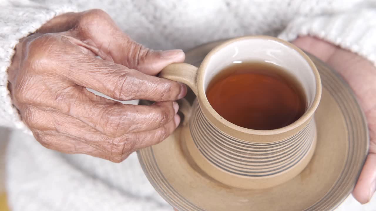 persona de edad avanzada sosteniendo una taza de té