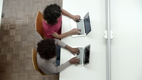 vista superior de mujeres escribiendo en computadoras portátiles en la biblioteca