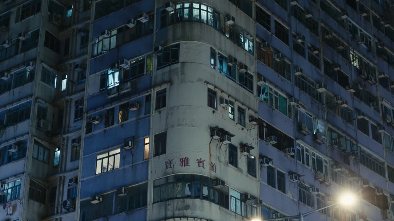 Vista panorâmica de edifícios de apartamentos e arranha-céus no centro de Hong Kong, China, à noite, iluminados pelas luzes da cidade e janelas brilhantes.