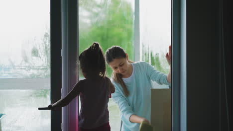 madre linda y hija pequeña lavan la ventana