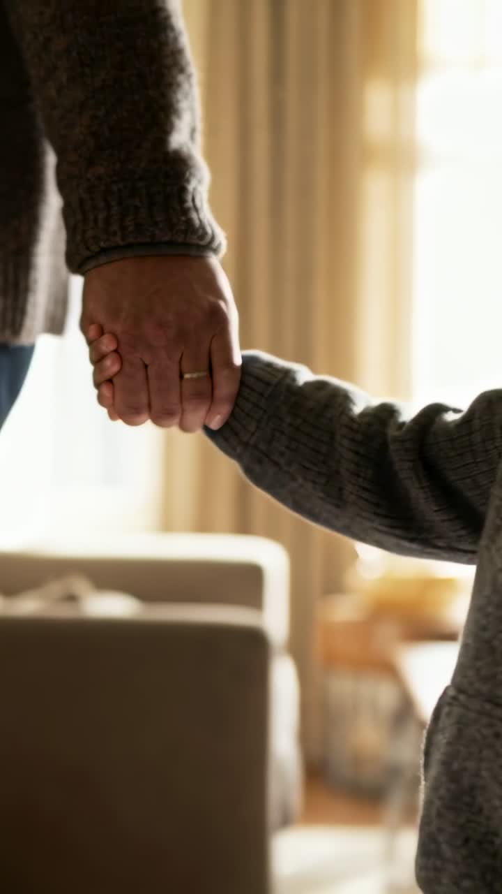 Video verticale: Bambino che si allunga afferrando la mano di un adulto, l'adulto si sposta a sinistra a casa, con maglione lavorato a maglia e anello.