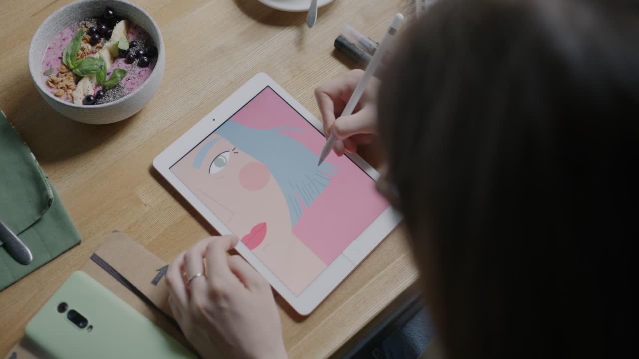 Woman drawing digital portrait in a coffee shop during breakfast