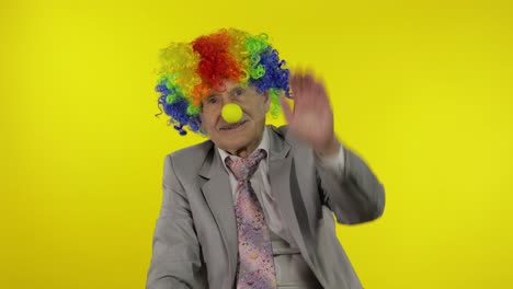 anciano payaso hombre de negocios empresario en peluca agita sus manos, sonriendo