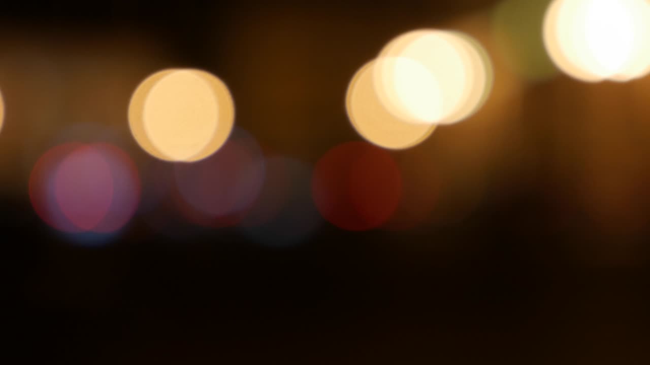 Beautiful glittering bokeh in dark blurry background at night. The round colorful bokeh shine from car lights on city street. Out of focus with blurry. Unfocused city lights. Traffic bokeh. Abstract concept