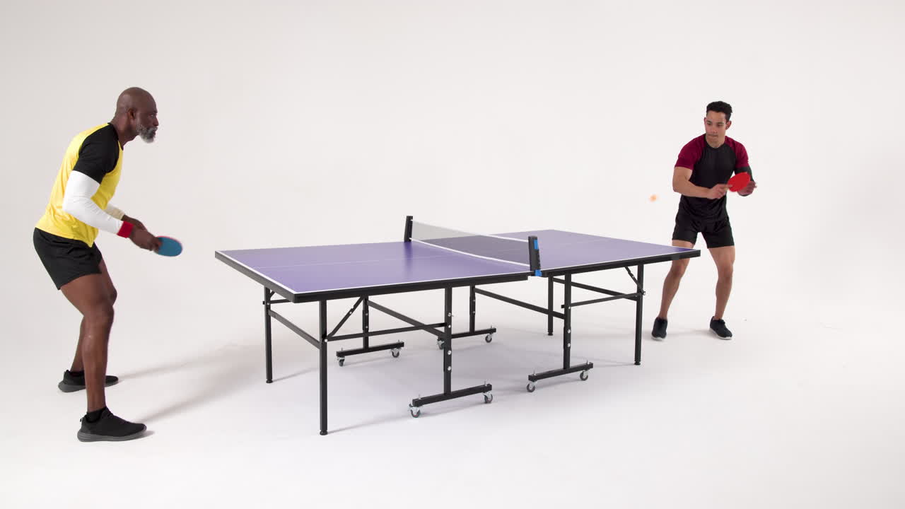 Playing table tennis, two men competing in friendly match indoors