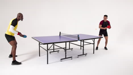 playing table tennis, two men competing in friendly match indoors