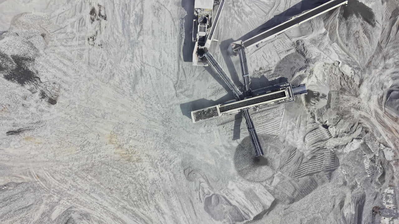 Large granite quarry shows heavy machinery and stone extraction process from an aerial view during daylight hours