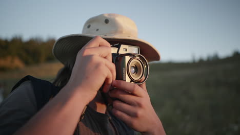 Hombre-Con-Sombrero-Y-Gafas-Toma-Fotos-De-La-Naturaleza-Con-Cámara-En-Hora-Dorada