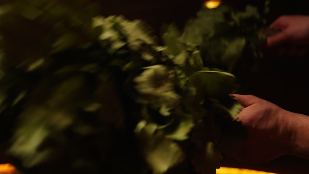 People holding a birch broom in a traditional Russian bath