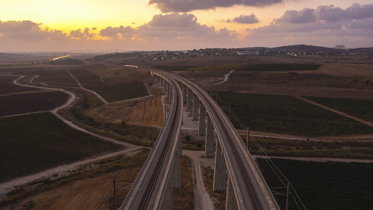Beautiful aerial hyperlapse of two trains passing over a massive railway bridge in an orange sunset