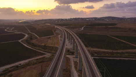 beautiful aerial hyperlapse of two trains passing over a massive railway bridge in an orange sunset