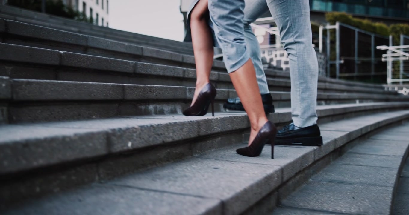 Business Couple Walking Up Stone Stairs in City