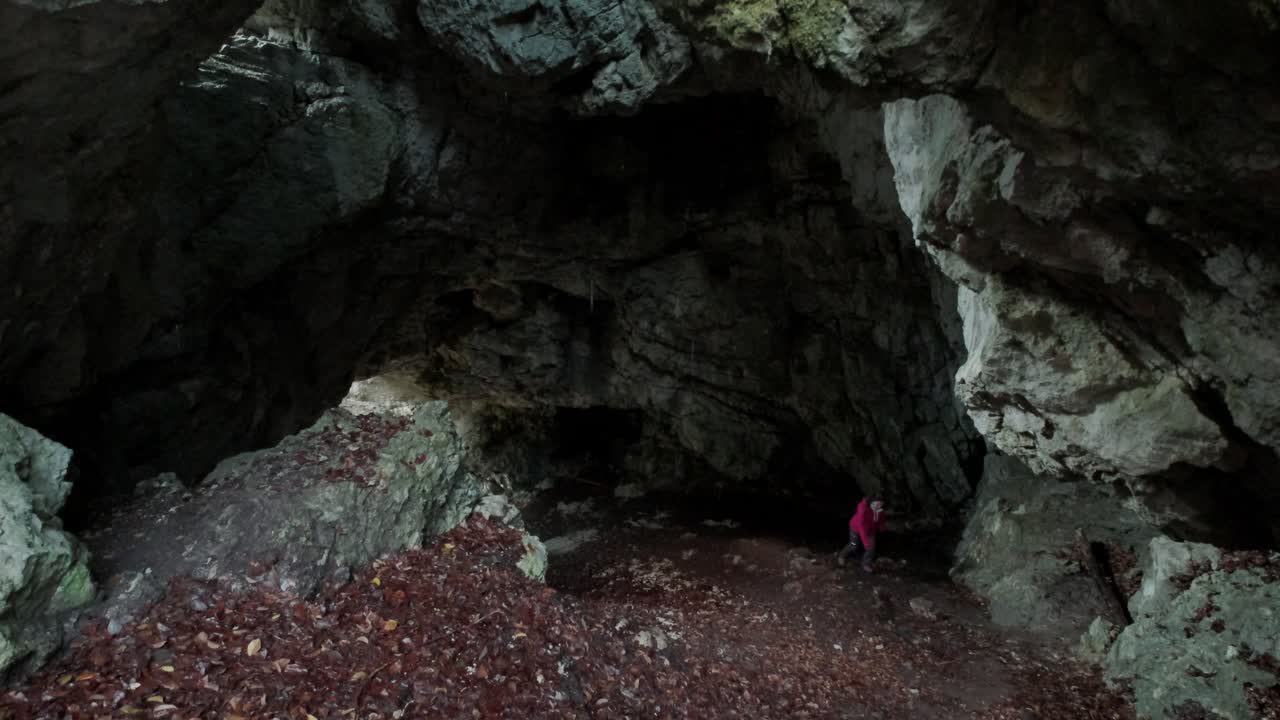 Lady walking up a steep section in the cave entrance. Camera looking down at the female as she struggles to walk up the section. Pokljuka Gorge in Slovenia Triglav National Park