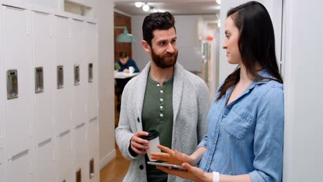 Business-executives-discussing-over-digital-tablet-in-locker-room