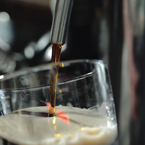 bartender pours a dark beer in glass. close-up. sqare video