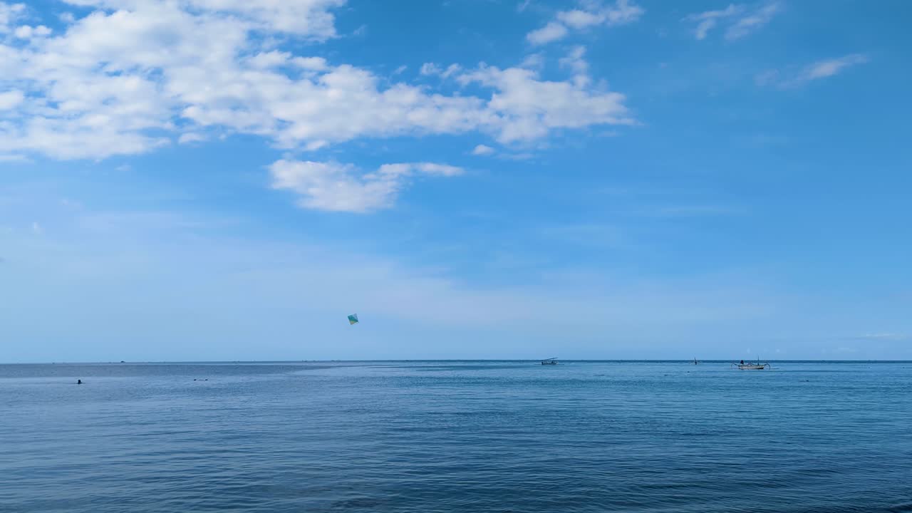 Kids flying a kite over blue ocean in Amed on tropical island of Bali Indonesia