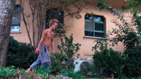 guy-doing-multiple-somersault-flips-bare-chest-in-sunny-garden